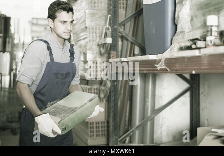 young male in uniform is choosing cement in the building store room Stock Photo