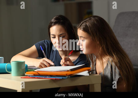 Two concentrated students studying together commenting notes at home late hours Stock Photo