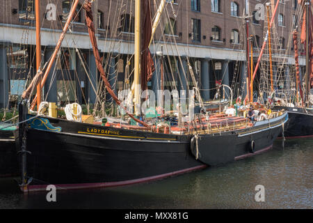 A traditional thames sailing barge or wooden cargo ship alongside in the heritage port of st Katherine dock in central London on the river thames. Stock Photo