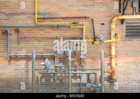 Copper pipes on a brick wall Stock Photo