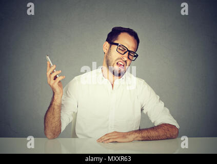 Man in white shirt and glasses grimacing and ignoring conversation partner while having phone call Stock Photo