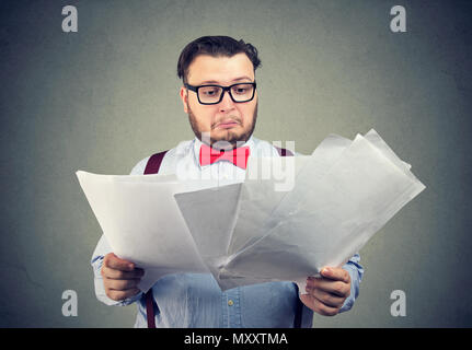 Formal man in glasses and bow tie exploring important documents looking dumbfounded with information Stock Photo