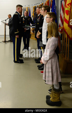 U.S. Army Col. Lance Varney (left), Commander of the U.S. Army Garrison (USAG) Bavaria,  prepares to recognize U.S. Army Master Sgt. Michael Saxton (back right), assigned to the 4th Battalion, 319th Airborne Field Artillery Regiment, 173rd Airborne Brigade, and his family during the USAG Quarterly Military Retirement Ceremony, in Vilseck, Germany, Dec. 9, 2016. (U.S. Army photo by Spc. Emily Houdershieldt) Stock Photo