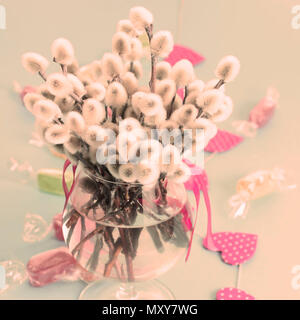 Festive arrangement in a Glass vase with twigs catkins. Bright Candy garlands on a pink background. Stock Photo