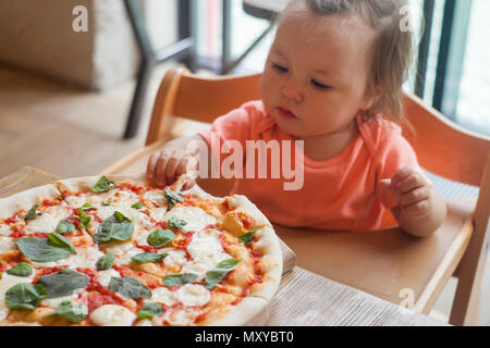 baby girl eating pizza in italian restaurant, Healthy, unhealthy food, children's fast food Stock Photo