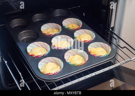 Muffin cups with cake batter arranged in baking tray overhead Stock Photo
