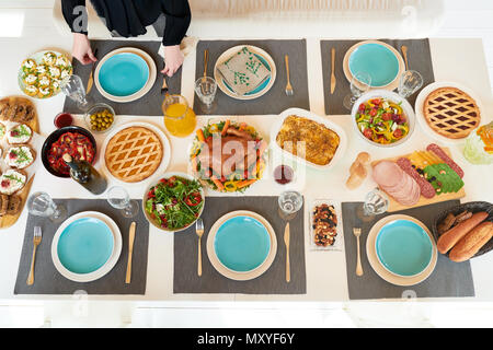 Above view of festive dinner table set for whole family with delicious homemade dishes, turkey and pies on it served with robin blue plates and napkin Stock Photo