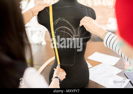 Back view  portrait of two women working in fashion design and collaborating on project , focus on sewing dummy traced for pattern making Stock Photo