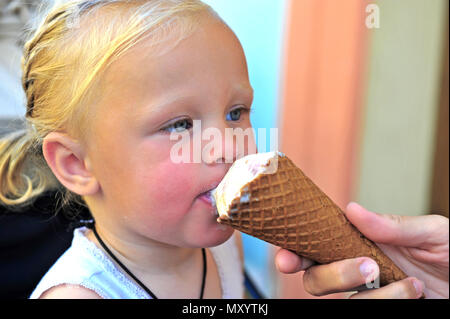 Little baby girl eating an ice-cream outdoors Stock Photo