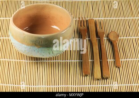 Japanese teacup with bamboo cutlery on vegetable mat. Spoon, two forks and a teaspoon. Stock Photo
