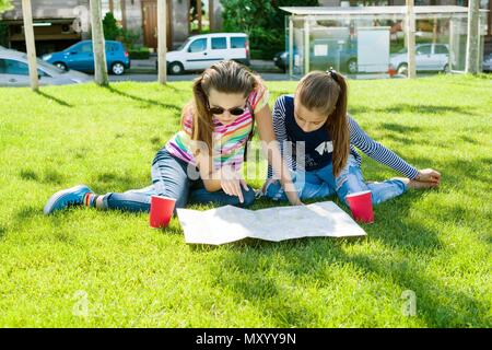 Young cute girls teens with map of european city outdoors. Stock Photo