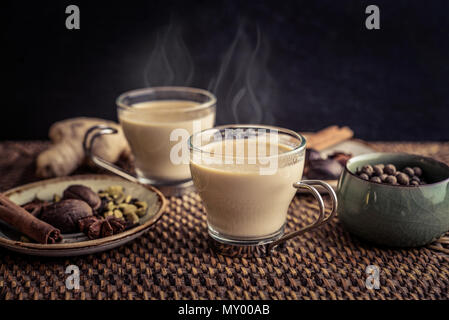 Traditional indian drink - masala chai tea (milk tea) with spices on rattan tray Stock Photo