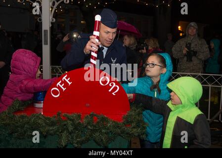 Col. Roman L. Hund, installation commander, flips the light switch from off to on during the annual Christmas Tree Lighting Ceremony with help from Anaily Garcia, left, Alexandria Kircher, center, and Hunter Kircher, right, outside the base chapel Nov. 30. Before the tree lighting, the Bedford High School A’Capella Ensemble and Hanscom Middle School band performed holiday music as children waited for the arrival of Santa Claus. (U.S. Air Force photo by Mark Herlihy) Stock Photo