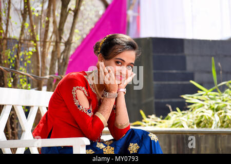 Young lady with hands on chin and Indian attire looking at camera, Pune Stock Photo