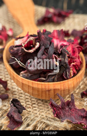 Dry hibiscus tea in wooden spoon closeup on burlap Stock Photo