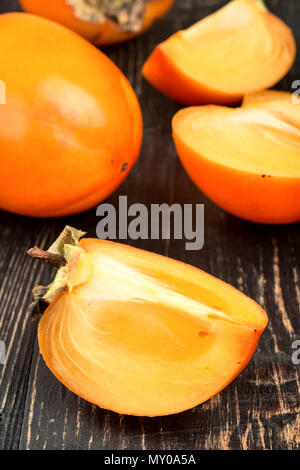 Fresh persimmon fruit with slice and half on wooden background Stock Photo