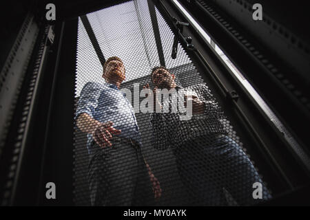 Pleased two colleagues examining server closet Stock Photo