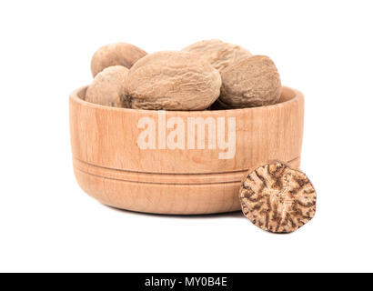 Dry nutmeg in a bowl with half on white background Stock Photo