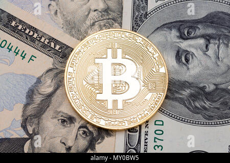 Golden bitcoin coin on us dollars close up. Stock Photo