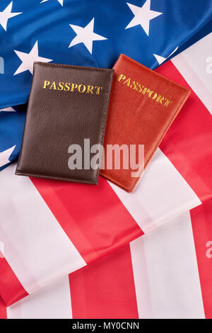 Two passports lying on American flag. Top view on USA flag with passports, vertical image. How to become USA citizen. Stock Photo