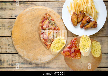 Fast food, crispy chicken wings,bread,french fries and pizza on wood background. Stock Photo