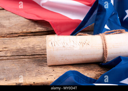 United States flag and rolled-up Constitution. United States Constitution and rolled-up document on old wooden planks, horizontal image. Stock Photo