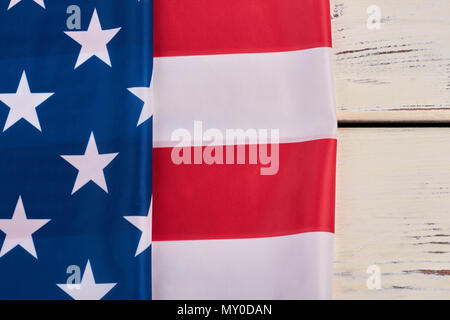 USA flag folded on white wooden background. Close up stars and stripes satin flag and copy space. Happy Independence Day. Stock Photo