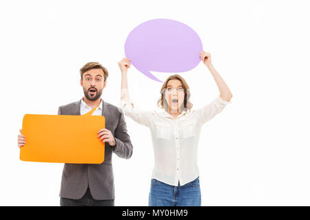 Portrait of an excited young business couple holding empty speech bubbles isolated over white background Stock Photo