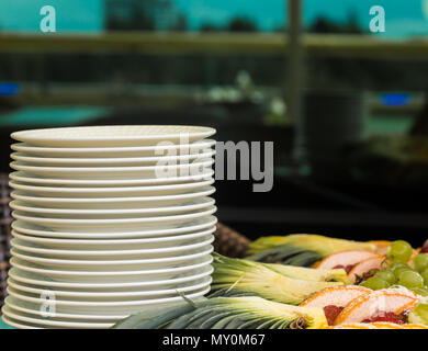 set white plates on the table, fruits in the background Stock Photo
