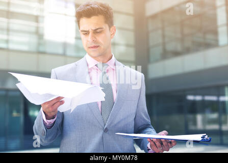 Businessman holding folder with documents and attentively reading Stock Photo