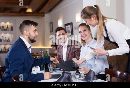 Smiling waitress taking order from guests, using digital tablet Stock Photo