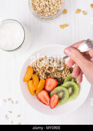 Granola with Greek yoghurt and fruit on a wooden background in a rustic ...