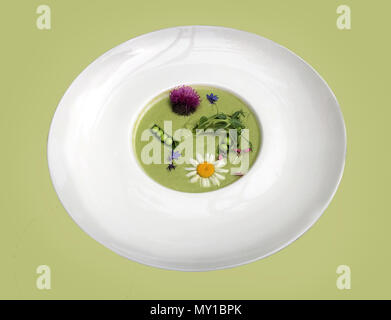 Vegetable soup mashed green peas and broccoli, decorated with flowers and fragrant herbs. Isolated Stock Photo