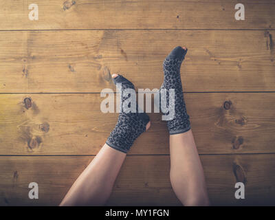 Overhead shot of a woman's feet in worn socks on the floor Stock Photo