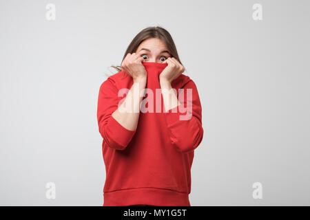 A girl with a social phobia hides her face in a sweater. Stock Photo