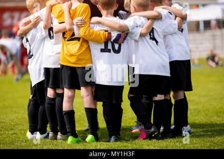 Kids sports team with coach. Team sports for children. Young boys standing together as a teammates having team briefing huddle with coach. Youth coach Stock Photo