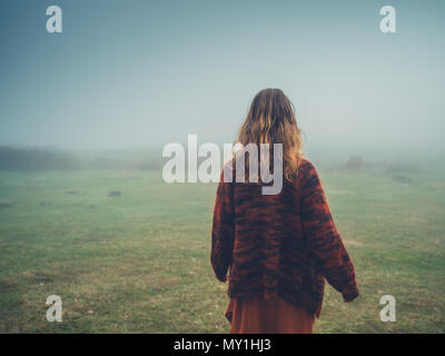 A young woman is walking in the fog on a moor Stock Photo