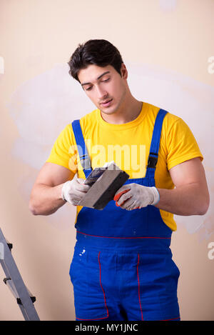 Young contractor employee applying plaster on wall Stock Photo