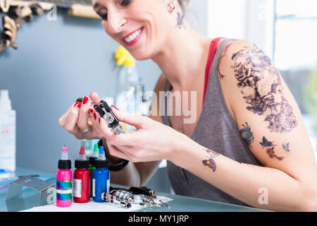 Close-up of the hands of a female artist preparing a professional tattoo machine Stock Photo