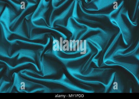 Close up of ripples in turquoise silk fabric. Satin textile background. Stock Photo