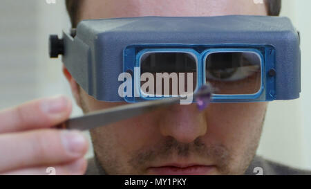 Master jeweler in special glasses looking at gem Stock Photo