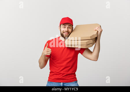 Pizza delivery concept. Young handsome delivery man showing pizza box and holding thumb up sign. Isolated on white background Stock Photo