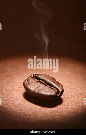 Roasted Turkish coffee bean with steam on brown background. Macro close up shoot. Stock Photo