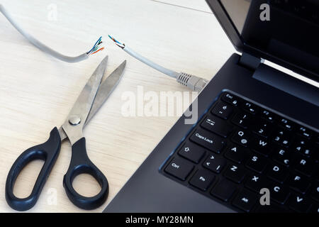 Internet cable connected to a laptop computer cut by a scissors. Concept of internet ban, cencorship and interruption. Stock Photo