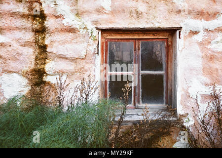 Vintage old window on grunge pink stone wall of an abandoned cottage Stock Photo