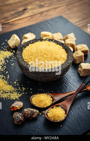 Brown cane sugar in bowl on black slate background closeup Stock Photo