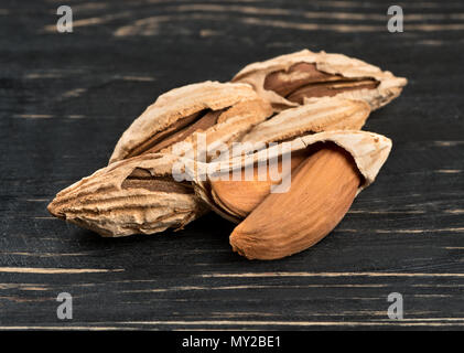 Wild uzbek inshell almonds on wooden background Stock Photo