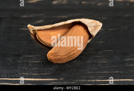 Uzbek open inshell almonds on wooden background, closeup Stock Photo