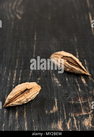 Two wild uzbek inshell almonds on an empty wooden background Stock Photo