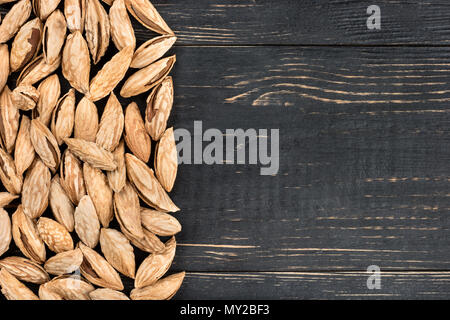 Scattered uzbek inshell almonds on an empty wooden background Stock Photo